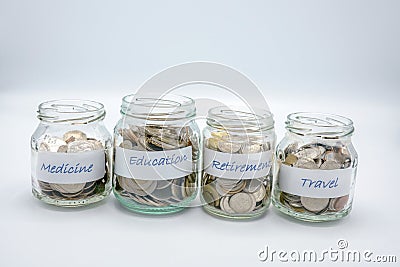 Four glass bottles filled with coins with label paper of medicine,education,retirement,travel Stock Photo
