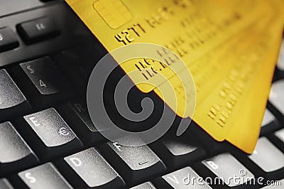 Four golden credit cards on black computer keyboard. E-commerce data and ebanking protection, internet and finance security Stock Photo