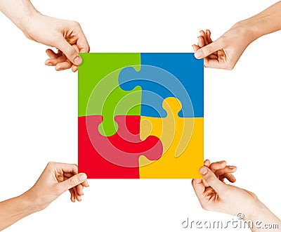 Four hands connecting puzzle pieces Stock Photo