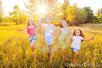Four happy beautiful children running playing moving together in the beautiful summer day. Stock Photo