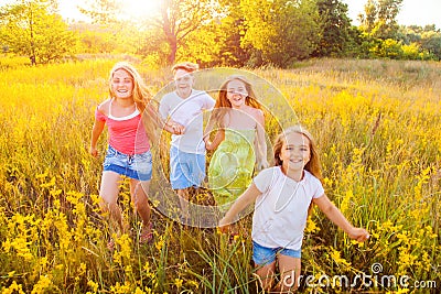 Four happy beautiful children running playing moving together in the beautiful summer day. Stock Photo