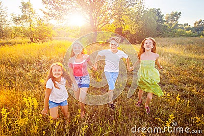 Four happy beautiful children running playing moving together in the beautiful summer day. Stock Photo