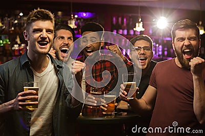 Four happy men holding beer mugs and gesturing Stock Photo