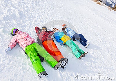 Four happy snowboarders lying in a row Stock Photo