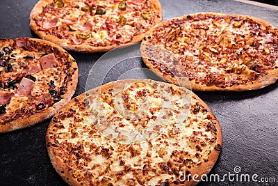 Four homemade different pizzas on dark wooden background Stock Photo