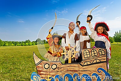 Four kids in pirate costumes behind ship Stock Photo