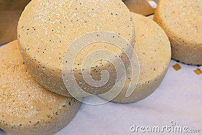 Four large heads of cheese lie on a white linen tablecloth. Different types of cheese. Useful dairy product. Production and sale Stock Photo