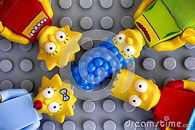 Four Lego Simpsons minifigures - Marge, Bart, Lisa, and Maggie, on gray background Editorial Stock Photo