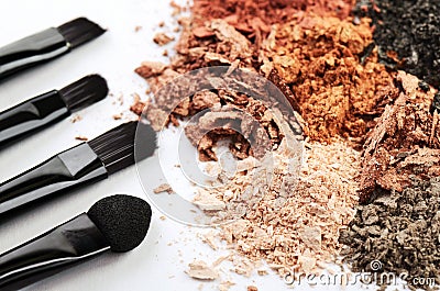 Four makeup brushes and crumbled eyeshadows of different colors Stock Photo