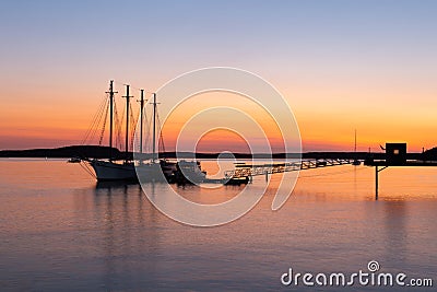 Four-mast sailboat anchored at the pier in Frenchman Bay during a pink and orange sunrise Stock Photo