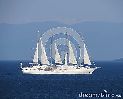 A four-mast white ship under sail moves across the blue sea Stock Photo