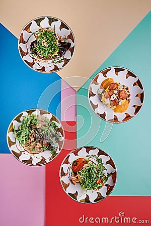 Four meatless dishes on a colored background. Vegetarian salads in beautiful plates. Top view. Series of photo for menu Stock Photo