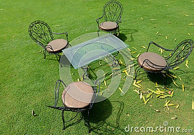 Four metal chairs in a grassy lawn Stock Photo