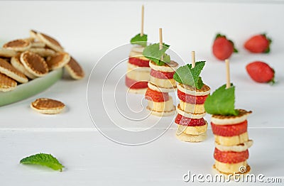 Four mini pancakes on a skewer with a mini banana, strawberries and fresh green mint. Stock Photo