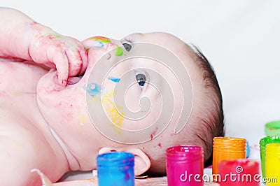 Four-months baby with multi-colored paints Stock Photo