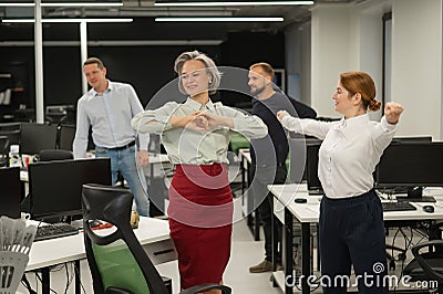 Four office workers warm up during a break. Employees do fitness exercises at the workplace. Stock Photo