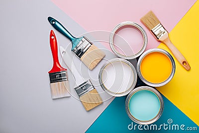 Four open cans of paint with brushes on bright background. Stock Photo
