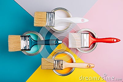 Four open cans of paint with brushes on them on bright symmetry background. Stock Photo