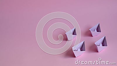 Four pastel purple paper boats on a light pink background. Stock Photo