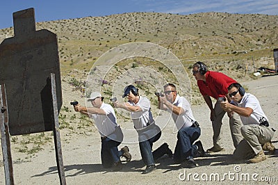 Four People Firing Guns At Shooting Range Stock Photo