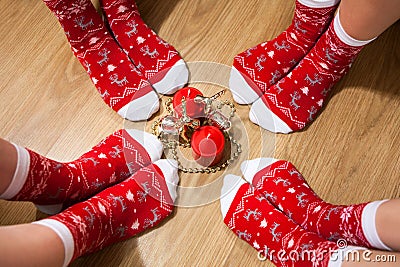 Four people legs wearing red socks with Christmas ornament placed around candles on the floor Stock Photo