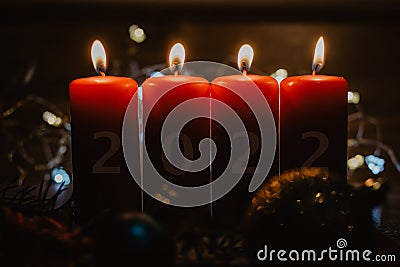 Four red Advent candles with 2022 figures on them and Christmas decorations lying in the snow as a template Stock Photo