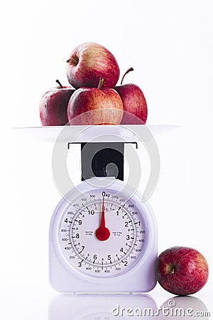 Four red apples on weighing scales portrait format Stock Photo