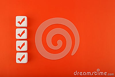 Four red checkmarks on white cubes in a row against red background with copy space Stock Photo