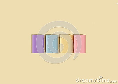 Four rubber erasers in pastel colors on a light yellow background. National rubber eraser day concept. Stock Photo