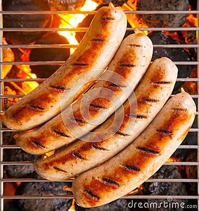 Four sausages called bratwurst, grilling over hot coals on a BBQ Stock Photo