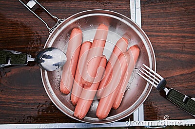 Four sausages frankfurter wurst boiling in hot water in pan. Stock Photo