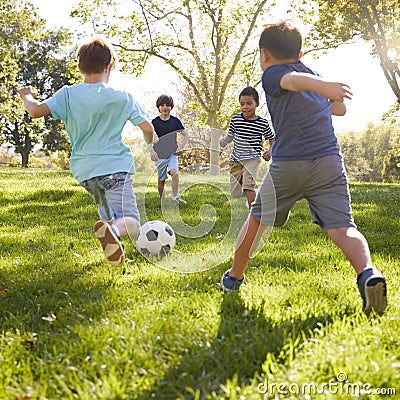 Four schoolboys playing football in the park, square format Stock Photo