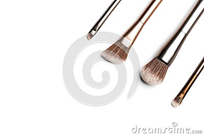 Four shiny bronze- and silver-coloured makeup brushes for applying powder, eyeshadow, eyeliner, bronzer and highlighter arranged Stock Photo