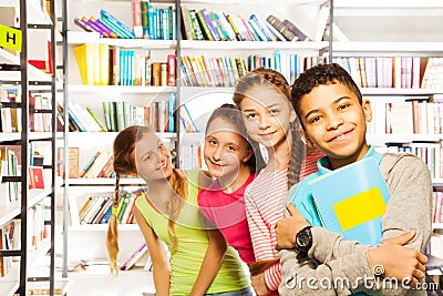 Four smiling kids standing in a row with books Stock Photo