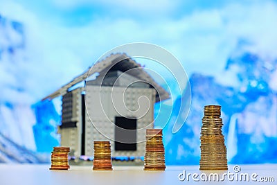 Four stacks of coins with size increasing from left to right, corresponding to each financial quarter, with a house in the back. Stock Photo