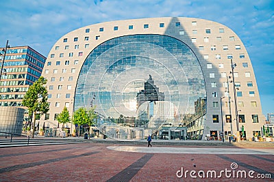 Four story Market Hall building glass facade reflects sky and surrounding buildings as sun sets and casts long shadows on pavement Editorial Stock Photo