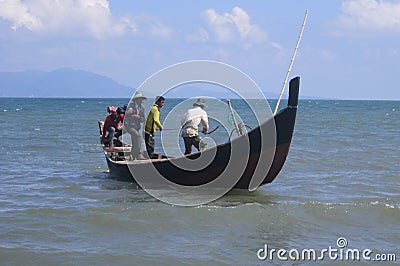 Four traditional fishermen on Alue Naga Beach, Banda Aceh, Indonesia, are working on a boat to operate a beach seine-type trawl be Editorial Stock Photo