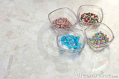 Four transparent glass cups with decorations for confectionery and baking on the marble background. Stock Photo