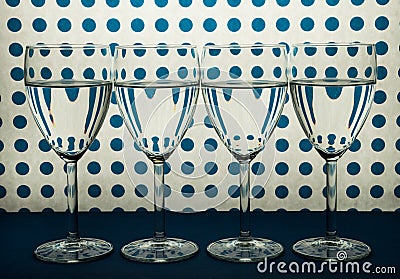 Four transparent glasses for wine standing in line and white background with blue spots. Stock Photo