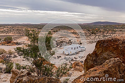 Four wheel drive vehicle and large white caravan camped beside a rocky outcrop. Stock Photo