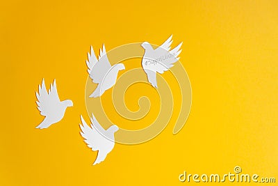 Four white paper dove birds as a symbol of peace isolated on yellow background. Peace to Ukraine. World Peace Day. Stock Photo