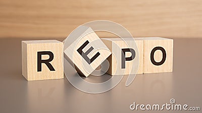 four wooden cubes with the letters REPO on the bright surface of a brown table, business concept Stock Photo