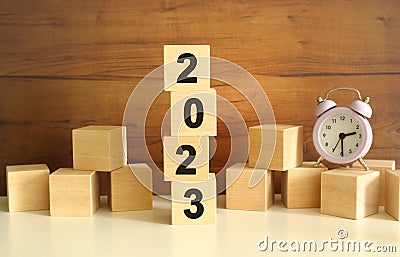 Four wooden cubes stacked vertically on a brown background form the word 2023. Stock Photo