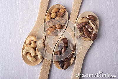 Four wooden spoons with brazilian nuts, cashews, barus and almonds Stock Photo