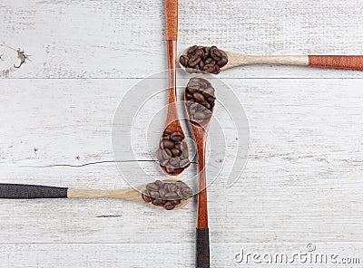Four wooden spoons with roasted coffee beans creatively arranged Stock Photo