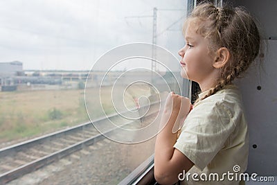 Four-year girl looks out the window of the train car Stock Photo