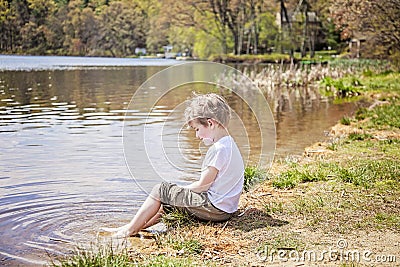 Boy sitting on shore of lake Stock Photo