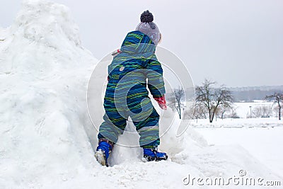 A four-year-old child, a boy, is climbing a snowy hill Stock Photo