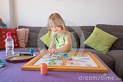 Little child playing parchis game at home in summer Stock Photo