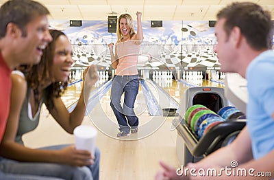 Four young adults cheering in a bowling alley Stock Photo